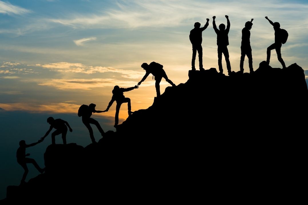 Ethical outsourcing team members climbing a mountain together.